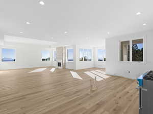 living room with light wood-style floors, a large fireplace, recessed lighting, and a raised ceiling