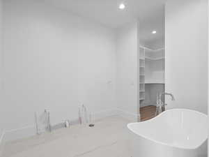 Primary bedroom bathroom with a freestanding bath, recessed lighting, and a walk in closet. Vanity coming soon!