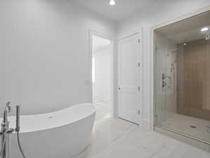 Primary bedrooms full bath featuring a freestanding bath, a shower stall, light marble finish floors, and recessed lighting