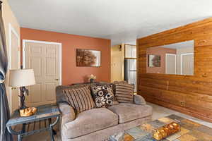 Living room with wooden walls, a textured ceiling, and stone tile floors