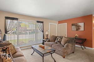 Carpeted living area featuring a textured ceiling and baseboards