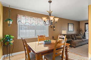 Dining area featuring a textured wall, wood finished floors, and a chandelier