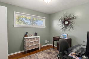 Office area featuring dark wood finished floors and a textured ceiling