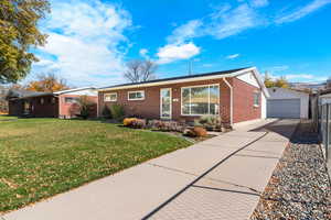 Single story home featuring an outdoor structure, brick siding, and a detached garage