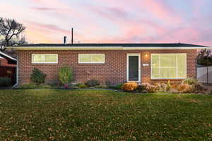 Single story home with brick siding and a lawn