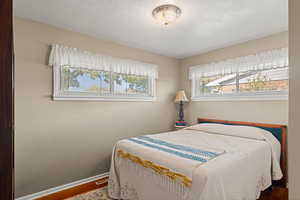 Bedroom featuring wood finished floors, multiple windows, and a textured ceiling