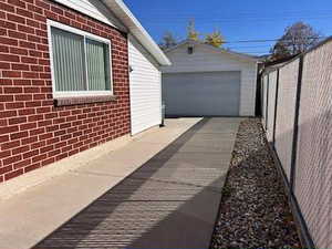 View of side of home with brick siding, an outdoor structure, and a detached garage