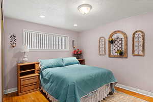 Bedroom featuring a textured ceiling, light wood-style floors, and recessed lighting