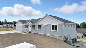 View of front facade featuring driveway, roof with shingles, board and batten siding, and a garage