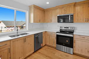 Kitchen with light brown cabinets, appliances with stainless steel finishes, light wood-type flooring, and recessed lighting