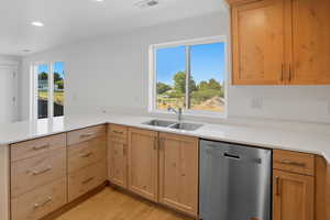 Kitchen with dishwasher, light wood-type flooring, light stone countertops, recessed lighting, and a peninsula