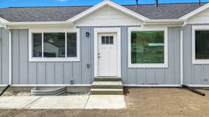 Property entrance featuring board and batten siding and roof with shingles