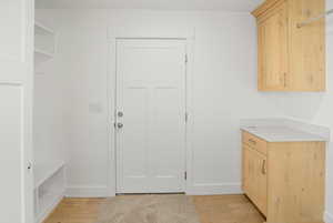 Laundry area featuring light wood-style floors and baseboards