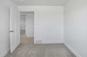 Spare room with light carpet and baseboards