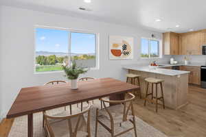 Dining room with light wood finished floors and recessed lighting