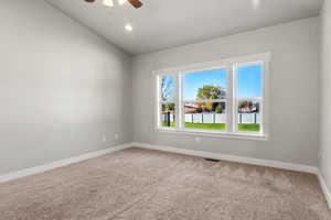 Carpeted bedroom with a ceiling fan and lofted ceiling