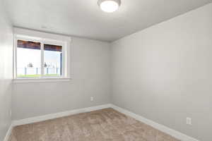 Carpeted spare room with baseboards and a textured ceiling