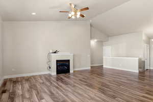 Unfurnished living room featuring a glass covered fireplace, wood finished floors, ceiling fan, recessed lighting, and high vaulted ceiling