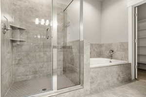 Bathroom featuring a shower stall, a bath, and tile patterned flooring