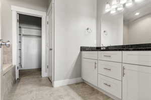 Bathroom with a spacious closet, vanity, and light tile patterned floors
