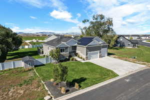 View of front of home with stone siding, roof mounted solar panels, concrete driveway, board and batten siding, and a mountain view