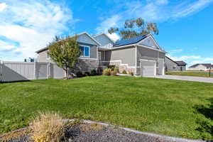 View of front of home with stone siding, solar panels, driveway, a gate, and board and batten siding