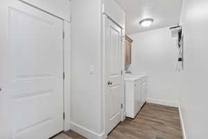 Laundry area with light wood-style flooring, washer and dryer, cabinet space, and a textured ceiling