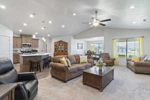 Living area featuring a ceiling fan, recessed lighting, lofted ceiling, light carpet, and a chandelier