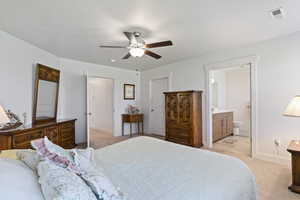 Bedroom with light colored carpet, a ceiling fan, ensuite bathroom, and a closet