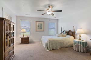 Bedroom featuring light carpet, ceiling fan, and a textured ceiling