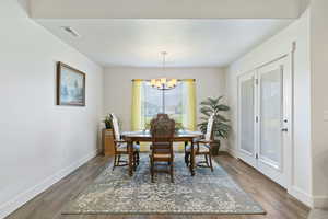 Dining room with wood finished floors and a chandelier