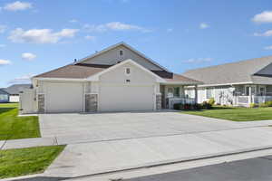 View of front facade with a porch, a garage, a front lawn, driveway, and roof with shingles