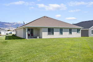 Rear view of property with a patio, a lawn, stucco siding, and roof with shingles