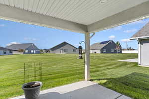 View of green lawn with a patio area and a residential view