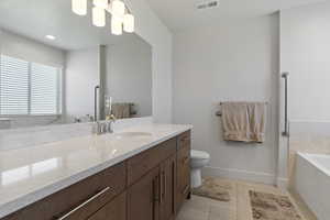 Full bath featuring vanity, a bath, light tile patterned floors, and recessed lighting