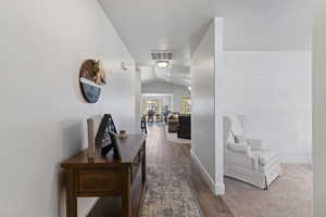 Corridor featuring vaulted ceiling and dark wood finished floors