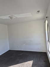Empty room featuring carpet and a textured ceiling