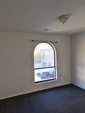 Unfurnished room with dark colored carpet and baseboards
