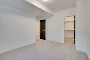 Unfurnished bedroom with light colored carpet and a spacious closet
