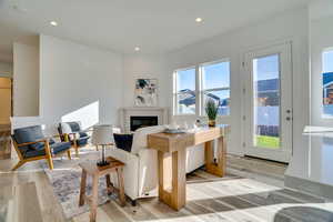 Living room featuring recessed lighting, light wood-type flooring, and a glass covered fireplace