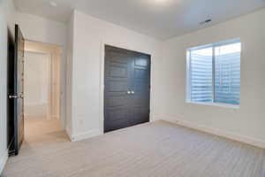 Unfurnished bedroom with light colored carpet and a closet