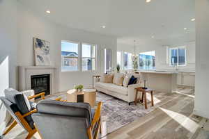 Living room featuring recessed lighting, light wood-type flooring, a premium fireplace, plenty of natural light, and a chandelier