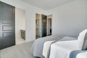 Bedroom with a walk in closet, ensuite bath, and light carpet