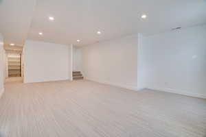Empty room with recessed lighting, light colored carpet, and stairs