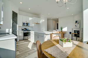 Kitchen featuring appliances with stainless steel finishes, light wood-style flooring, recessed lighting, a center island, and white cabinets