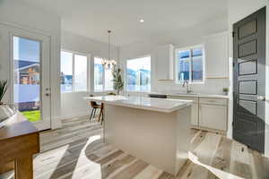 Kitchen with light wood-style floors, a center island, hanging light fixtures, a chandelier, and recessed lighting