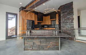 Kitchen featuring dark stone counters, modern cabinets, a kitchen bar, decorative light fixtures, and black refrigerator with ice dispenser
