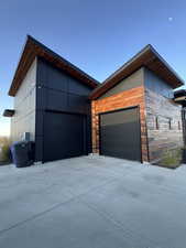 View of side of home featuring stone siding, concrete driveway, and an attached garage