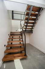 Staircase featuring finished concrete floors and baseboards