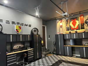 Miscellaneous room with built in desk, a garage, stairway, and rail lighting